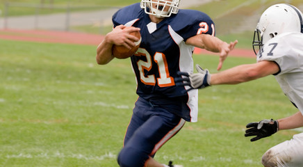 football running back with ball trying to be tackled