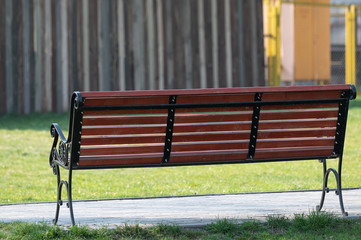 Empty wooden bench with forged details in a city park. place for thought and relaxation. green...