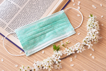 Coronavirus pandemic isolation , protection mask on a book and blooming branch