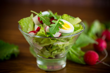 spring salad with arugula, boiled eggs, fresh radish, salad leaves in a glass bowl