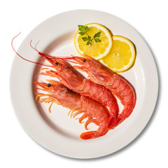 Macro close-up of a plate with three large red prawns, raw, fresh. Dish garnished with two round slices of lemon and parsley leaf. Isolated on white background. Ready for cooking