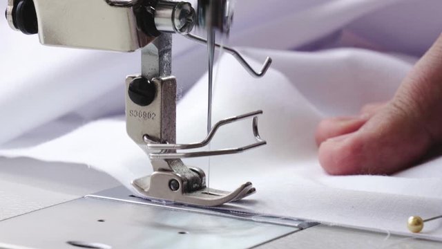 Detail of working sewing machine, close up of white fabric
