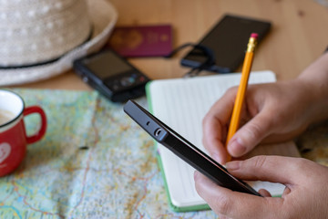 Woman drinking coffee, taking notes and exploring destination for vacation or travel, using smartphone.. Traveler's accessories, vacation items, Travel concept background. Planning a vacation trip.