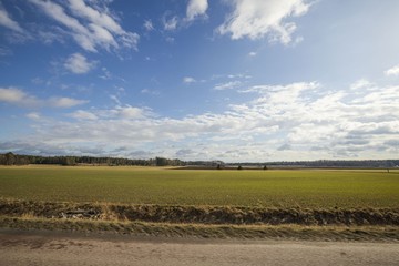 Beautiful landscape view with fields, forest trees and blue sky with white clouds. Gorgeous spring backgrounds. Sweden.