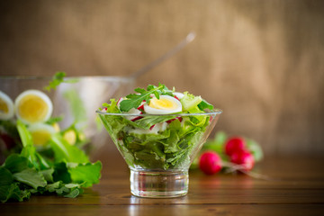 spring salad with arugula, boiled eggs, fresh radish, salad leaves in a glass bowl