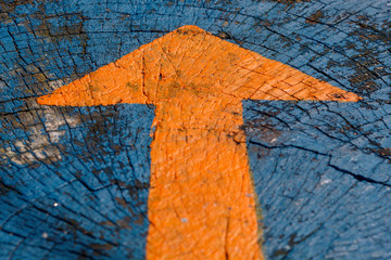 Orange Painted Arrow on Blue Painted Wooden Background