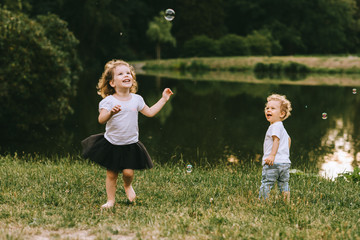 Handsome young father and beautiful mother in sunny summer nature playing with their cute small childrens