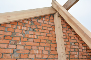 Obraz premium The beginning of roofing construction installing roof beams, trusses and braces to make a roof frame.