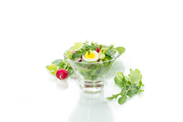 spring salad with arugula, boiled eggs, fresh radish, salad leaves in a glass bowl