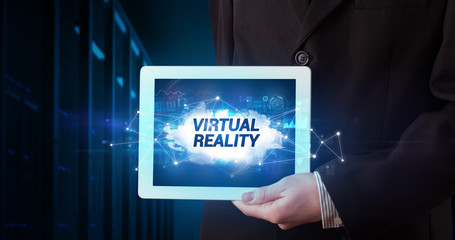 Young business person working on tablet and shows the inscription: VIRTUAL REALITY