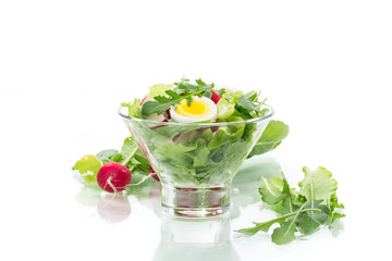 spring salad with arugula, boiled eggs, fresh radish, salad leaves in a glass bowl