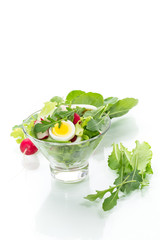 spring salad with arugula, boiled eggs, fresh radish, salad leaves in a glass bowl