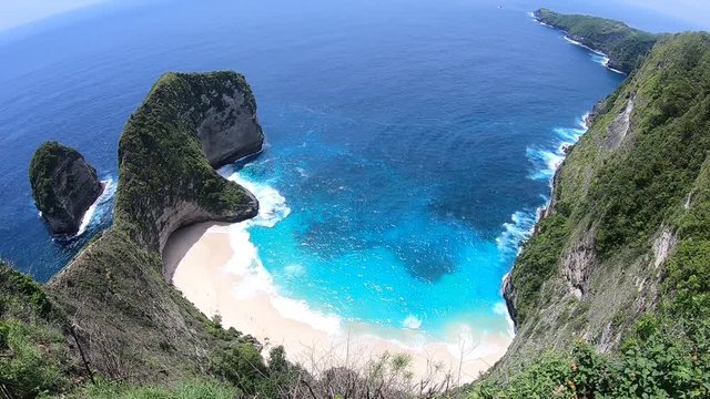 Famous Kelingking Beach on Nusa Penida, a small island in Indonesia near Bali. Turquoise ocean water and dramatic sea bluffs surround beautiful white-sand beach.