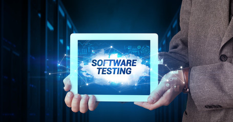 Young business person working on tablet and shows the inscription: SOFTWARE TESTING