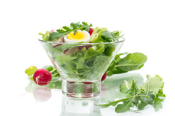 spring salad with arugula, boiled eggs, fresh radish, salad leaves in a glass bowl