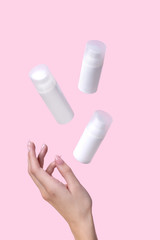 Open jar with cosmetic cream with womans hand on pink background