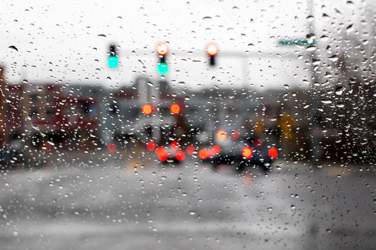 Raindrops on the windshield of a car with a green street light lit up. 