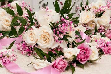Wedding composition for room decoration from
 cream and pink roses, ruskus leaves, pink gypsophila and ribbons.Close up, selective focus