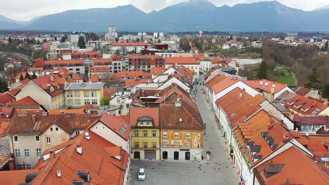 Forward low flying drone aerial over historic downtown area of Kranj town, Slovenia that starts to ascend and reveals the entire town