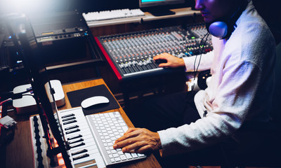 male music producer, composer arranging a song in home recording studio. music production technology concept