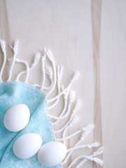 Easter uncolored white and brown eggs on a light blue and wooden background with flowers decoration