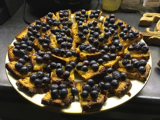 Cake with jam and blue berries neatly arranged on plate, sitting on kitchen counter