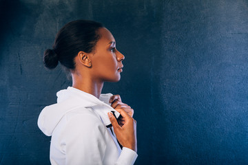 Side view of sporty woman wearing a sport clothes and looking away against black background 