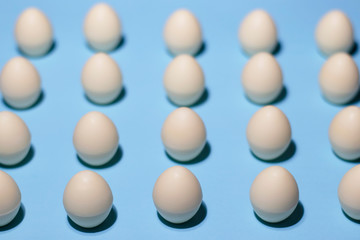 Pattern of white chocolate eggs on a pale blue. The parallel lines of chocolate eggs are shot close. Delicate photo specially for your Easter design and any other creative design.