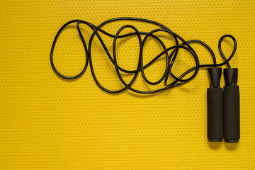Top view of a jump rope on the yellow mat. Sport at home, fitness and cross fit practice