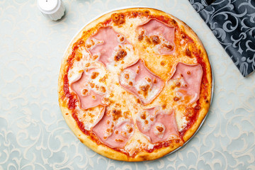 Pizza with ham and cheese on white plate