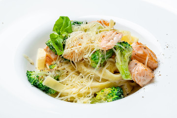 tagliatelli pasta with salmon and broccoli on white plate