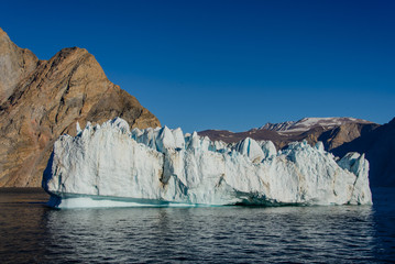 Fototapeta na wymiar Greenland landscape with beautiful coloured rocks and iceberg.