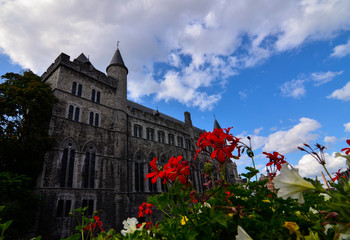 Fototapeta na wymiar Ghent,Belgium,August 2019.Geraard de Duivelstraat Castle.The main facade overlooks the water: it is an example of the medieval buildings of the city.Blue sky with white clouds.Planters along the canal