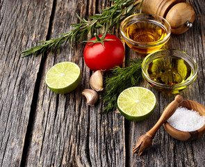 Tomato, lime, olive oil with spices  on wooden background. Top view. Rustic style.