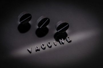three black pills on a dark background. vaccination. vaccine inscription