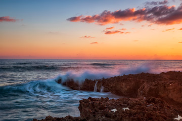 Splash of seawater at colorful sunset on coral rocks. Caribbean Cuba