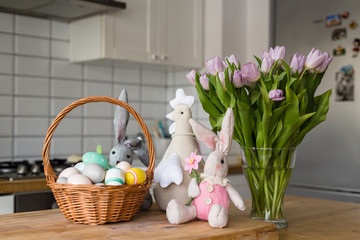 Easter decorations in the kitchen - a blackboard with greetings, basket with eggs, bunny, tulips and hen