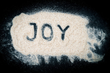 Top view of Joy word written on sand