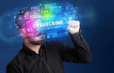 Businessman looking through Virtual Reality glasses with CYBERCRIME inscription, innovative security concept