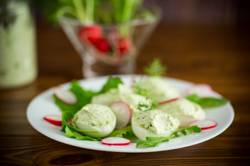 boiled stuffed eggs with green cheese filling with arugula leaves and radish