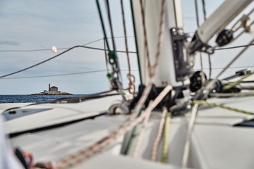 Croatia, Adriatic Sea, 19 September 2019: The race of sailboats, a lot of ropes, bright colors, view of lighthouse through ropes and mast