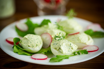 boiled stuffed eggs with green cheese filling with arugula leaves and radish