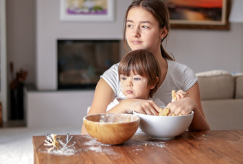 Happy siblings baking homemade cookies together at home. Children leisure activity at quarantine. Family cooking Easter bread