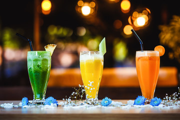 Side view on three of different healthy organic delicious fruit and vegetable smoothies in glasses on the wooden table with blurry bokeh background, horizontal format