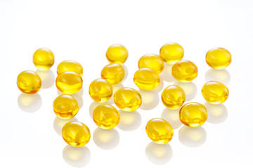 Yellow gel capsules pills. Capsules with yellow medicine on isolated white background. A lot of capsules vitamin D close-up . Bright oil yellow pills.