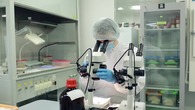 A scientist works with a microscope in the laboratory. Conducts research