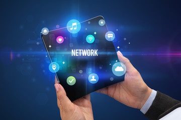 Businessman holding a foldable smartphone with NETWORK inscription, social media concept
