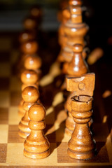 Close up image of chess board and chess pieces with lopsided sunlight and shadows