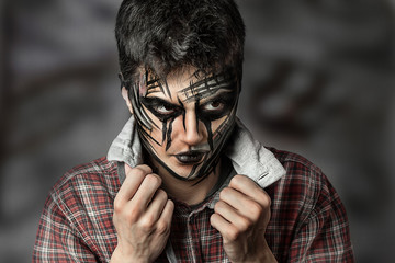 close up portrait of guy with halloween makeup on dark background. professional black face painting