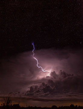 Lightening strikes above the clouds with exploding purple sparks